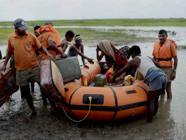 बाढ़ में फंसे लोगों को बचाते लोग 