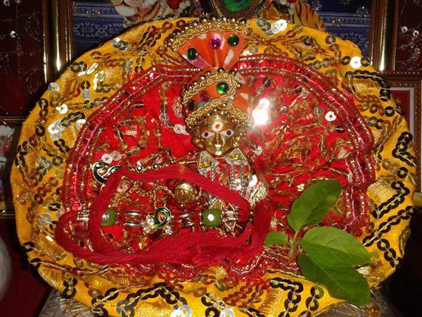 पीले और लाल रंग के कपड़े से सजाए भगवान को