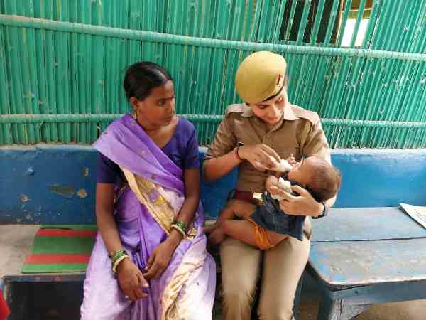 woman police constable feeding baby with milk on her lap woman police constable feeding baby with milk on her lap