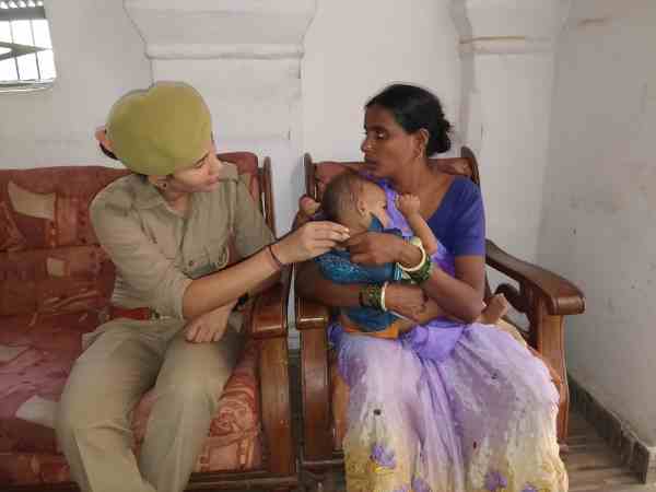 woman police constable feeding baby with milk on her lap woman police constable feeding baby with milk on her lap