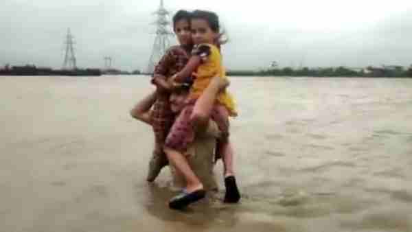 Gujarat police constable carried two children on his shoulders in flood waters Gujarat police constable carried two children on his shoulders in flood waters