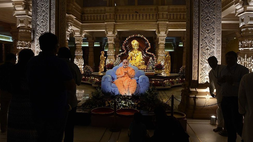 गांधीनगर के अक्षरधाम मंदिर में स्वामीनारायण की मूर्ति के सामने प्रमुख स्वामी का जीवंत चित्र गांधीनगर के अक्षरधाम मंदिर में स्वामीनारायण की मूर्ति के सामने प्रमुख स्वामी का जीवंत चित्र