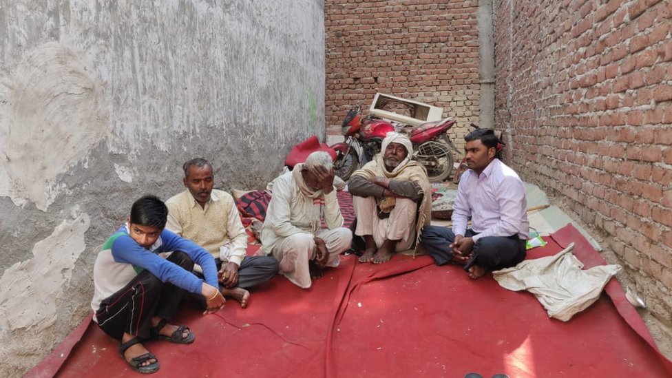 संजना के घर के बाहर बैठे कुछ रिश्तेदार संजना के घर के बाहर बैठे कुछ रिश्तेदार