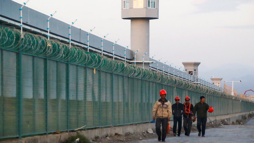 Workers walk by the perimeter fence of what is officially known as a vocational skills education centre in Dabancheng in Xinjiang Uighur Autonomous Region, China September 4, 2018. Workers walk by the perimeter fence of what is officially known as a vocational skills education centre in Dabancheng in Xinjiang Uighur Autonomous Region, China September 4, 2018.