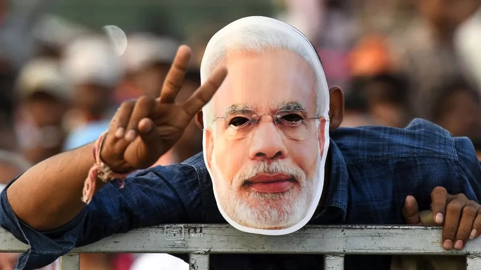 मोदी का मास्क लगाए एक शख़्स मोदी का मास्क लगाए एक शख़्स